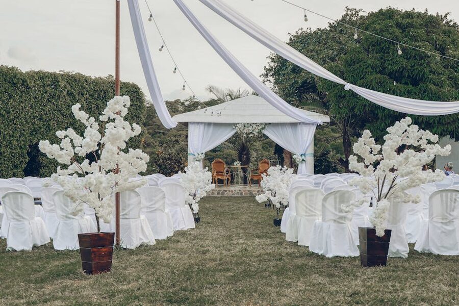 Outdoor wedding ceremony arrangement with white chairs and floral decorations