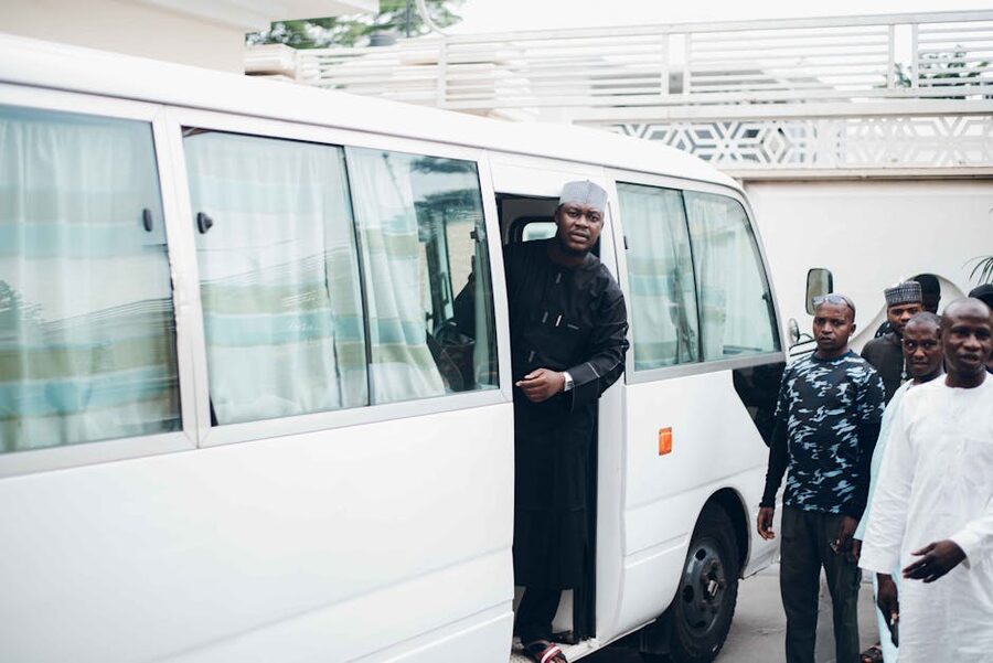 Group of friends boarding a white tour minibus
