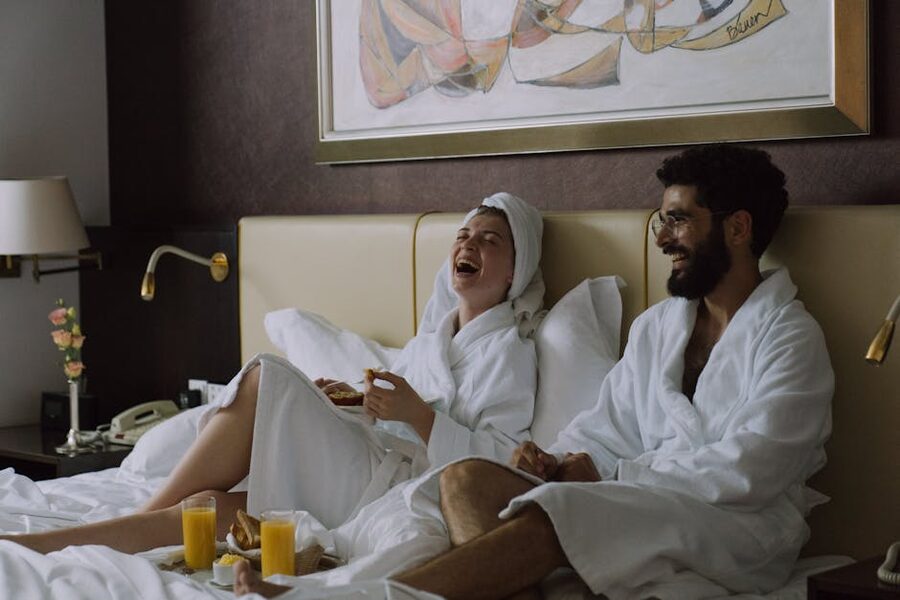 Couple in bathrobes laughing while having breakfast in bed