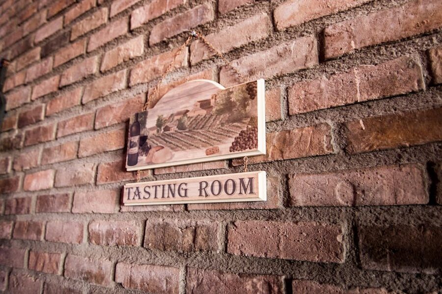 Quaint tasting room sign on a rustic brick wall