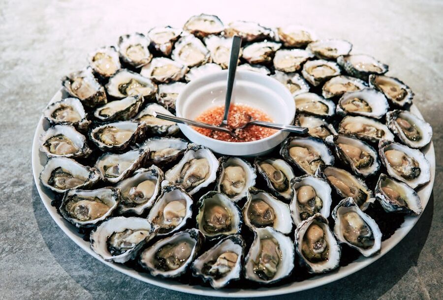 A platter of fresh oysters with sauce on ice