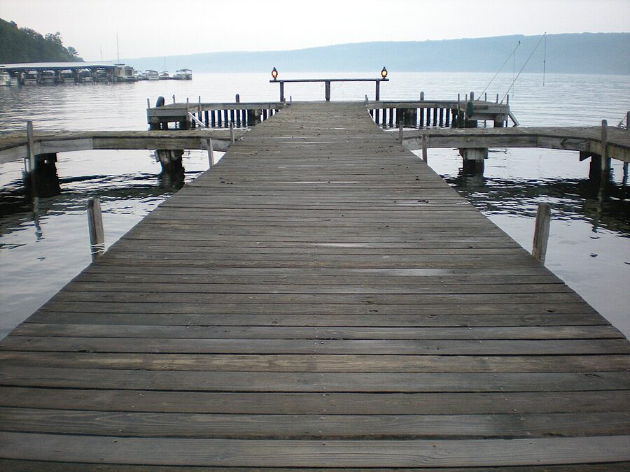 A wooden pier extends into Keuka Lake at sunset